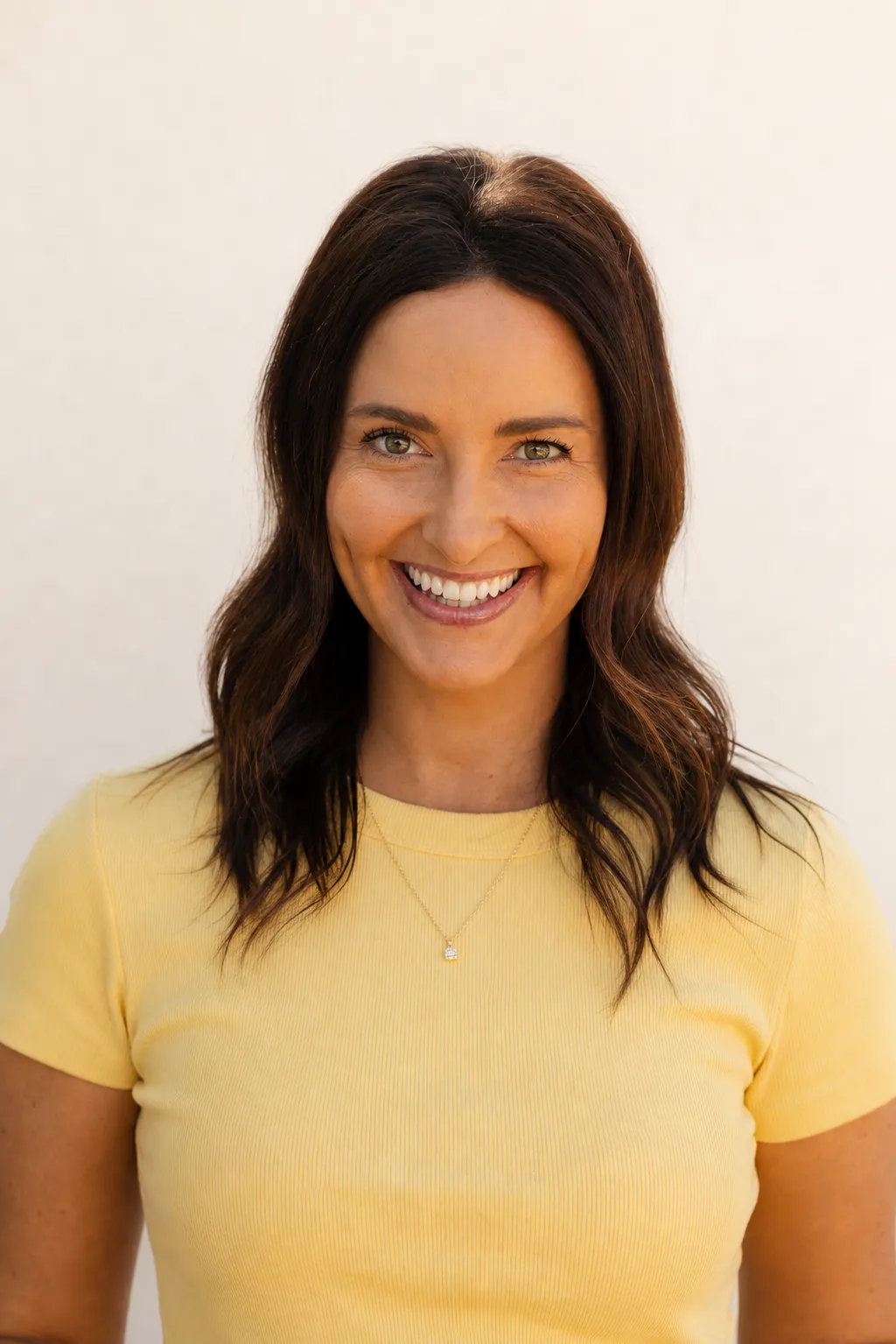 Katie Hahn in a yellow shirt against a warm cream background