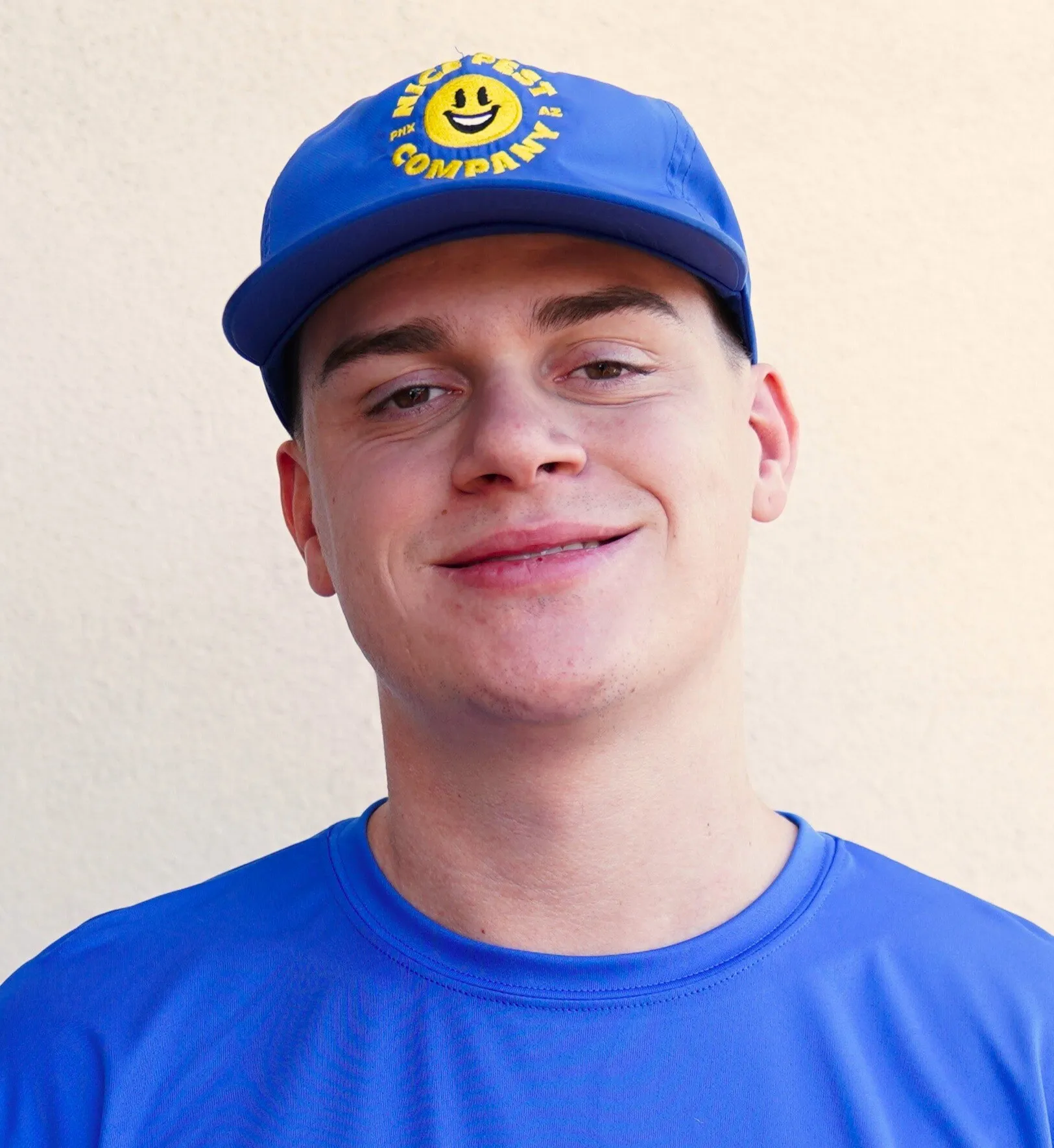 Mason Von Ronne wearing a blue Nice Pest Company shirt and cap